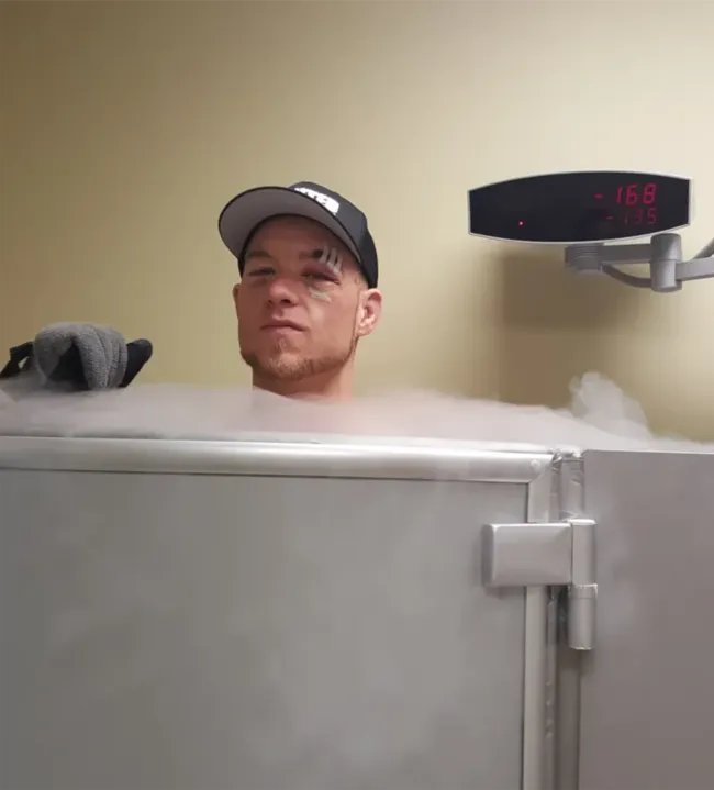 Athlete in cryotherapy chamber with cold vapor mist